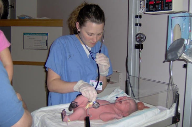 Nurse examining newborn baby with stethoscope in hospital